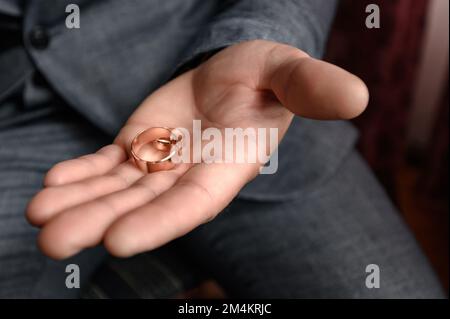 The groom is holding two wedding rings, hand and ring close-up. Stock Photo