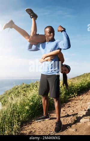 Strong guys get the good chicks. a muscular man carrying his girlfriend over his shoulders. Stock Photo