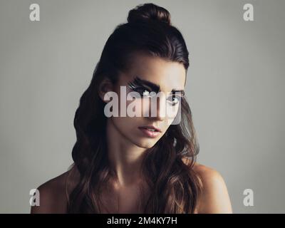 I prefer the flaws. Studio shot of an attractive young woman wearing bold eye makeup. Stock Photo