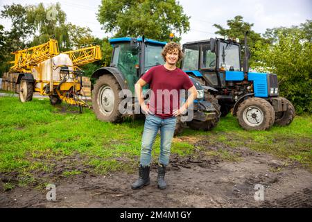 Joyous farmer standing in front of the tractor Stock Photo