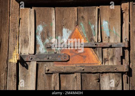 iron sign with skull and bones warning of danger on wooden old door as background Stock Photo