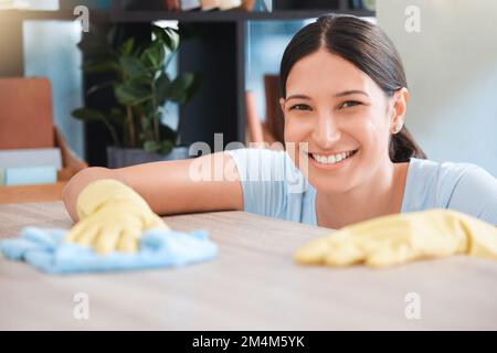 Cleaning, woman or portrait happy cleaner with cloth and gloves for dusty, messy or dirty bacteria on wooden table. Smile, cleaning service or girl Stock Photo