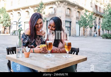 Friends drinking a beer and using the mobile outdoors Stock Photo