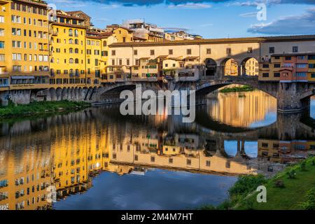 Colourful reflections of east elevation of Ponte Vecchio and buildings on the south bank of the Arno at sunrise in Florence, Tuscany, Italy Stock Photo