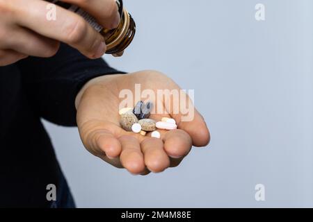 Drug abuse concept, hand of a woman with hypochondria problem pouring several pills Stock Photo