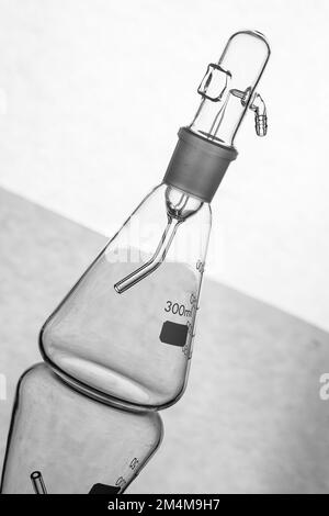 Silhouette of a glass flask with empty nebulizer, backlit on a reflective surface and isolated on a white background, laboratory glassware Stock Photo