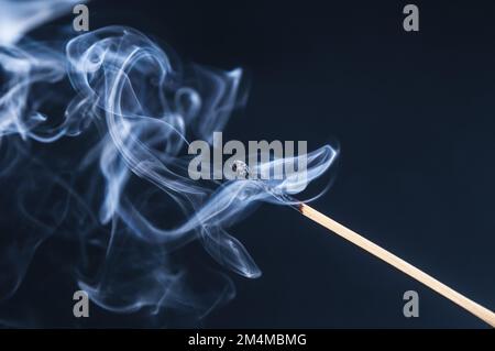 Burnt matchstick with smoke on a dark background Stock Photo