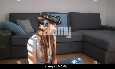 Young woman using virtual reality equipment, VR glasses, to look around the artificial world Stock Photo