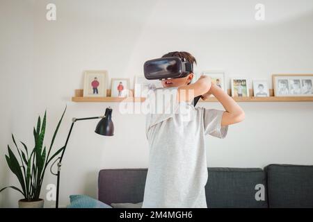 Boy having fun playing simulation games, using virtual reality headset and controller. Children and modern technology concept. Stock Photo
