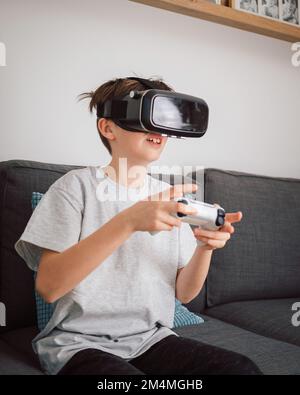 Boy having fun playing simulation games, using virtual reality headset and controller. Children and modern technology concept. Stock Photo