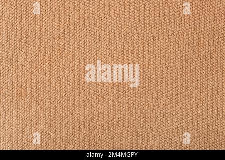 Knitted beige background. Large knitted fabric with a pattern. Close-up of a knitted blanket. Horizontal ornament. Stock Photo