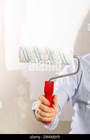Men hand painting wall with paint roller with white color. Painting apartment, renovating concept Stock Photo