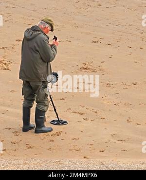 Man using a metal detector, on a beach, near Filey, North Yorkshire, England, UK, YO14 9LA Stock Photo