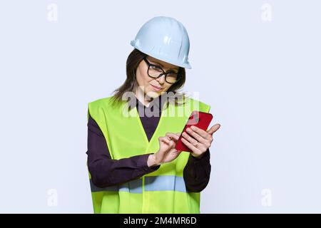 Woman industrial worker in helmet vest with smartphone Stock Photo