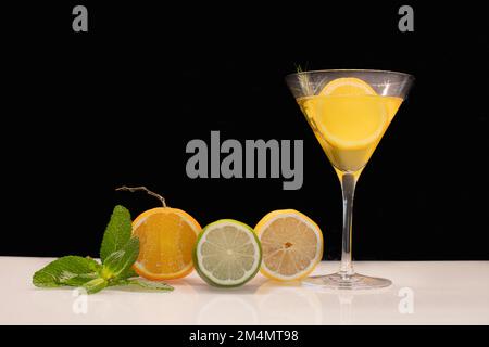Yellow cocktail glass with fruits on black background. Stock Photo