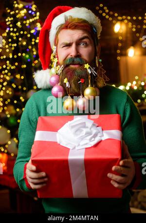 Santa man with decorated beard for New Year. Bearded male with Christmas gift. New year present box Stock Photo