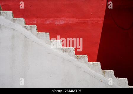 Red and white abstract zigzag staircase with a partial dark shade Stock Photo