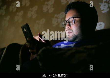 young men sitting on sofa using smart phone at night  Stock Photo