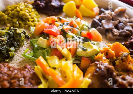 Plate with Injera bread with different topics like meat, salad, and vegetables. Injera is a traditional bread in Ethiopia. Stock Photo