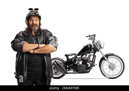 Mature bearded biker with a helmet and leather jacket in front of a chopper isolated on white background Stock Photo