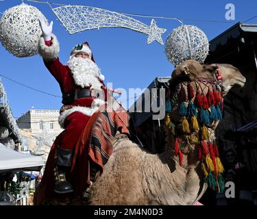 Jerusalem, Israel. 22nd Dec, 2022. Issa Kassissieh, dressed as Santa Claus, waves from a camel in the Old City of Jerusalem, on Thursday, December 22, 2022, days before Christmas. Photo by Debbie Hill/ Credit: UPI/Alamy Live News