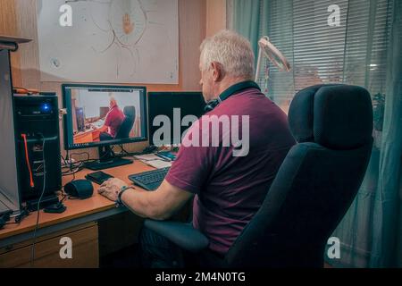 Old senior man in front of his computer with reflextion on the screen Stock Photo
