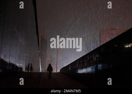 KYIV, UKRAINE - Dec. 16, 2022: Lone passers-by are seen emerging from an underpass at night during a snowfall during a blackout in Kyiv. Stock Photo