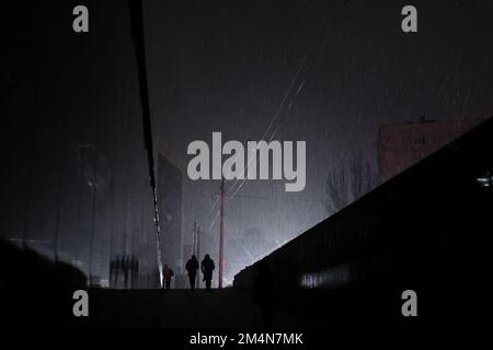 KYIV, UKRAINE - Dec. 16, 2022: Lone passers-by are seen emerging from an underpass at night during a snowfall during a blackout in Kyiv. Stock Photo