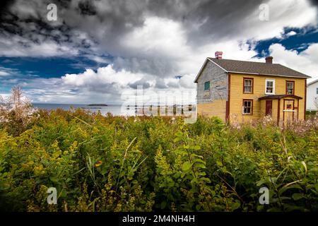 Abandoned home overlooking the Atlantic Ocean in fall colours near Elliston Newfoundland Canada under a deep blue dramatic sky. Stock Photo