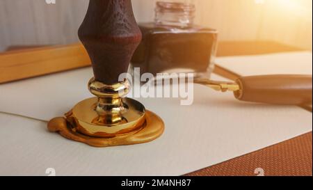 Authentic official luxury letter with a gold sealing wax stamp. Writing a letter with an old classic fountain pen dipped in ink and wax stamp seal. Stock Photo