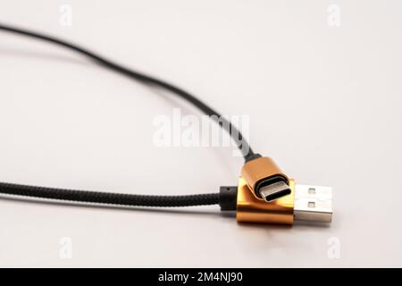 detailed close up of a black braided USB 2 to USB-C male cable with golden colour connectors Stock Photo