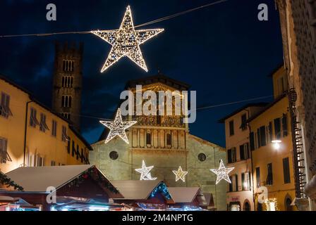 Christmas in Lucca. Christmas market with stars in front of St Frediano medieval church Stock Photo