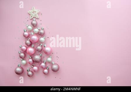 Christmas tree made of stars, confetti, pink balls on pink background. Flat lay, top view. Xmas greeting card with text - Merry Christmas. Stock Photo