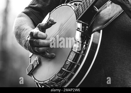 Close-up of mature man playing five string banjo, musical instrument, outside in black and white close-up of hand and fingers bluegrass music Stock Photo