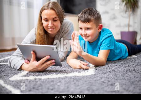 Happy mother and son greeting online looking at web camera using tablet pc Stock Photo