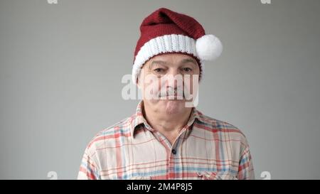 sad senior man wears Christmas Santa hat posing feeling alone and upset. Happy New Year 2023 celebration holiday concept Stock Photo