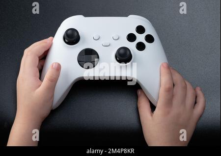 Wireless game controller in kid hand above top view isolated on black background Stock Photo
