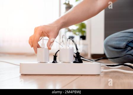 Plugging electrical plug on floor, socket at home. Energy efficiency concept Stock Photo