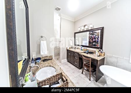 A large master bathroom with tile floors, dark wood vanity cabinets and a freestanding bathtub Stock Photo