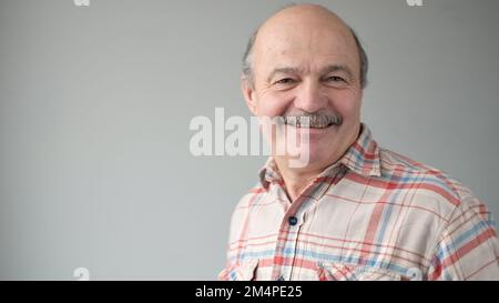 Portrait of smiling mature man standing on gray background. Studio shot Stock Photo