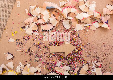 Arrow cut out of paper amid pencil shavings on canvas Stock Photo