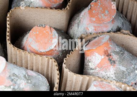 Old, used and weathered clay flower pots are separated from each other with an intermediate layer of cardboard. Stock Photo