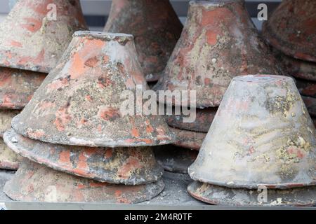 Old, used and weathered clay flower pots are stacked in a row. Stock Photo