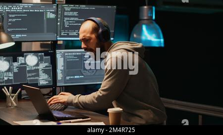 Cheerful app developer playing air guitar with keyboard, having fun and acting silly after hours. IT engineer fooling around with instrument and enjoying late night working in office, happy man. Stock Photo