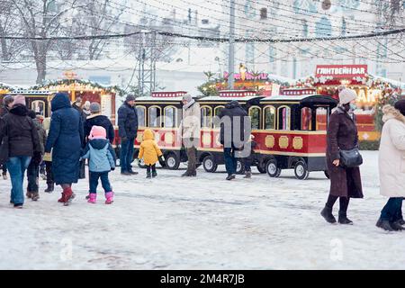 Kyiv, Ukraine - January, 2022: Christmas outdoor fair with Christmas tree, church, carousel and lights at the evening at snowy day. Festive holidays before war. Stock Photo