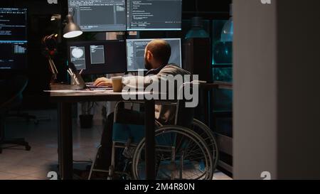 App developer with physical disability working on IT software coding, using source code and big data. Programmer wheelchair user with impairment developing new user interface. Stock Photo