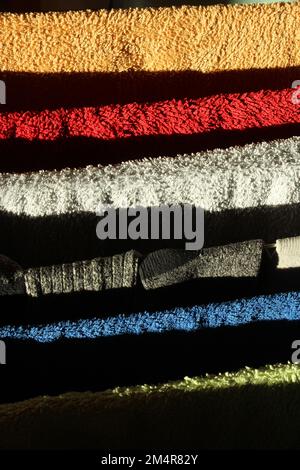 Plain, bright towels on a clothes horse drying with natural light casting dramatic shadows. Domestic abstract background with bold colours and design Stock Photo