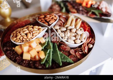 Assorted appetizers table with different antipasti, variations of nuts, pistachios, almonds, peanuts, charcuterie, snacks, cheese. Finger food for buf Stock Photo