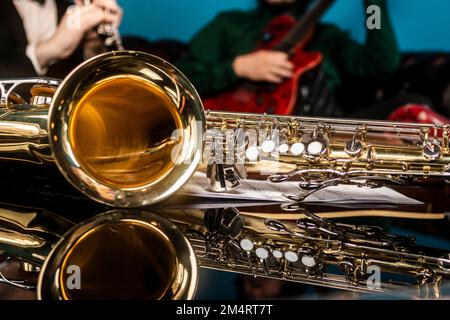 A gold and silver saxophone on a mirrored table Stock Photo