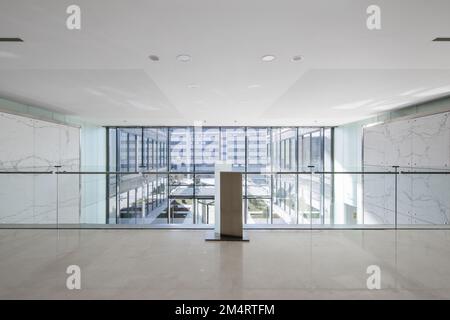 Atrium of an office building with green marble tiled walls, cream marble floors viewed from a mezzanine bay window with glass railing Stock Photo